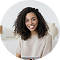 Portrait of a smiling woman with dark curly hair looking at the camera in a circular frame.